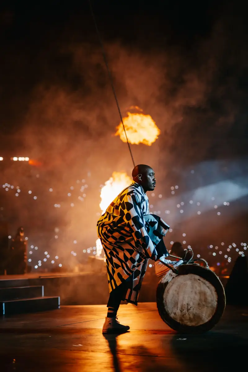 Drummer performing under stage lighting